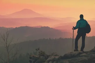 a man standing on top of a mountain, silhouetted against a vibrant sunset